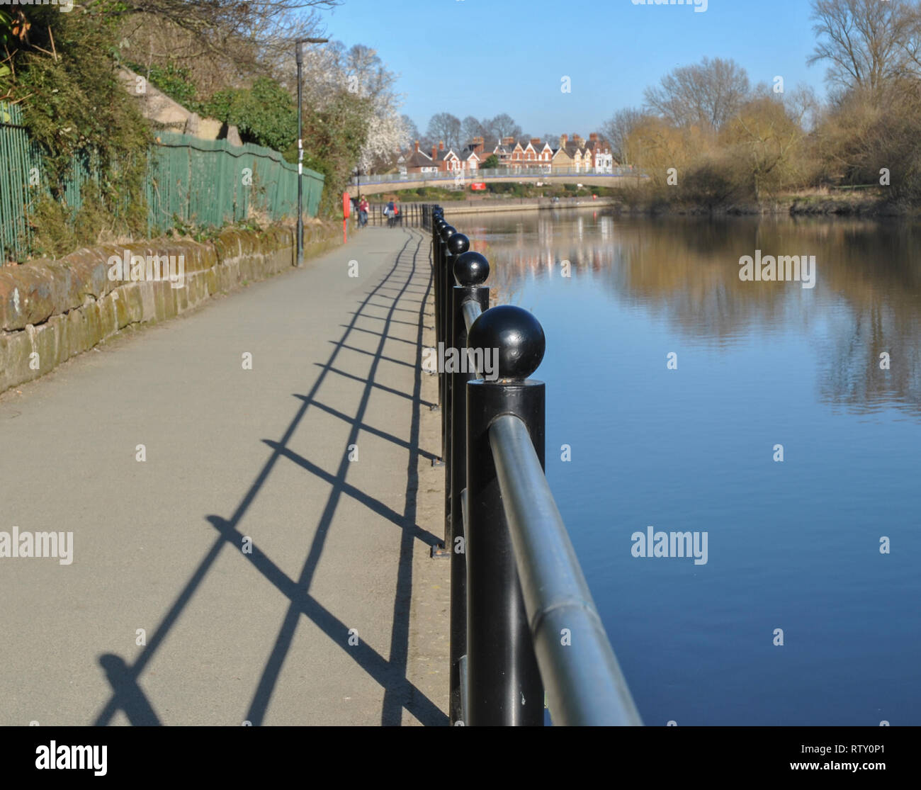 Ein Foto von Geländer entlang des Flusses in Shrewsbury, Schatten auf dem Weg gezoomt Stockfoto