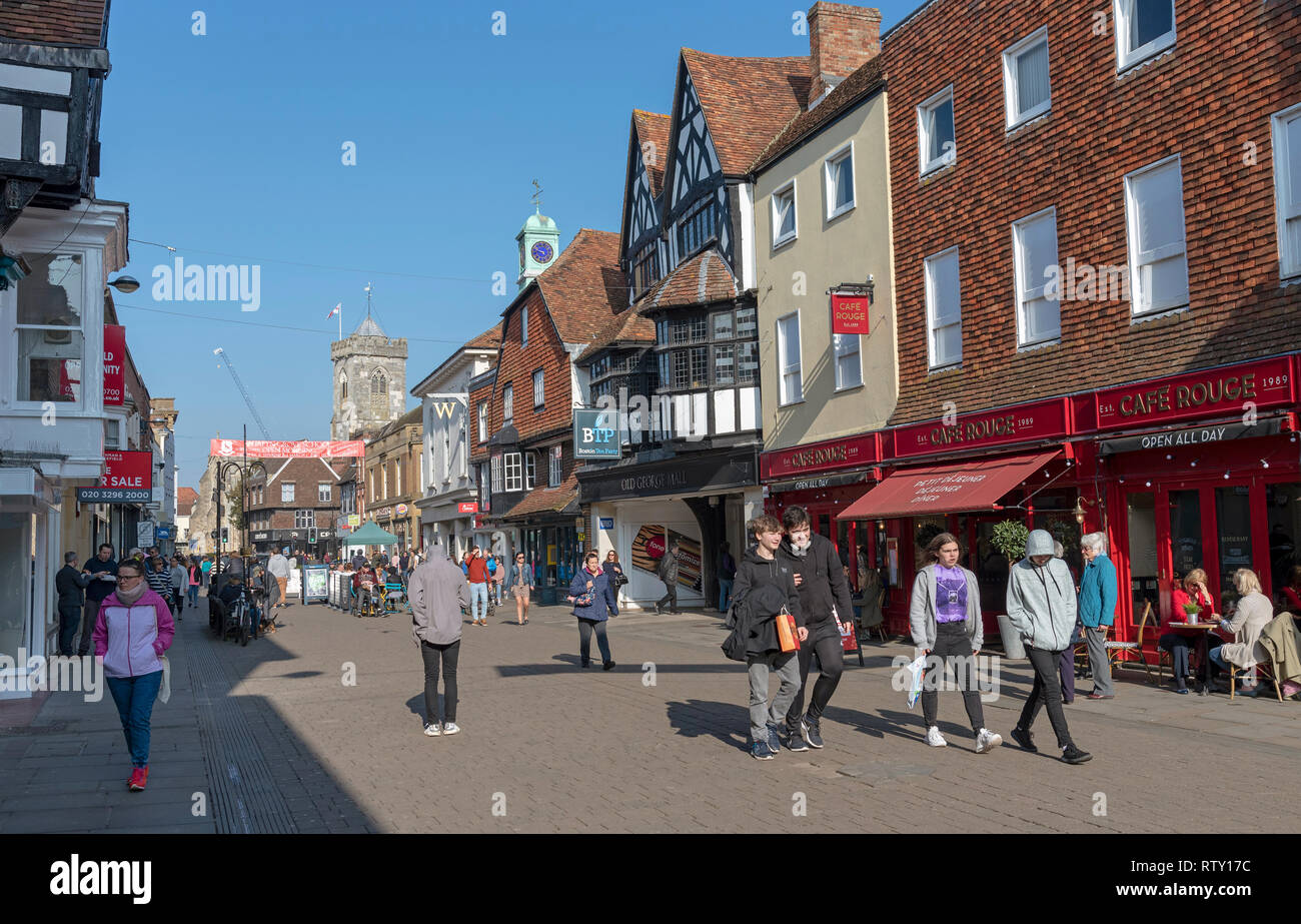 High Street, Salisbury, Wiltshire, England UK. Februar 2019. Käufer an der High Street in der Nähe der Eingang zum alten George Mall. Kirche Turm Stockfoto