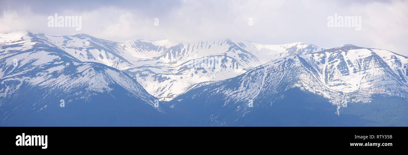 Panorama der Berge mit schneebedeckten Gipfeln. Frühling Landschaft mit schmelzenden Schnee in den Bergen Stockfoto