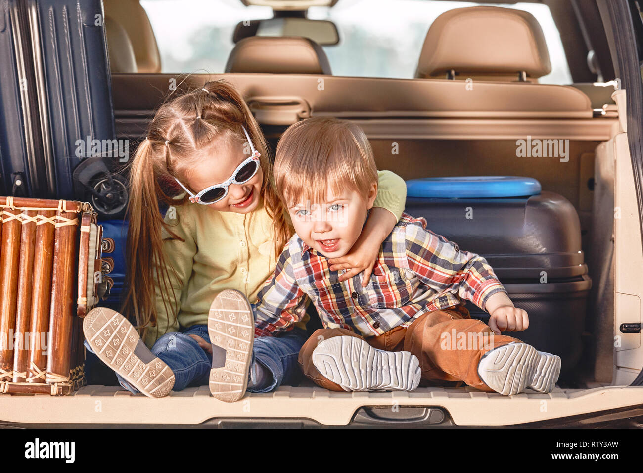 Zwei adorable kaukasischen Kinder im Kofferraum eines Autos sitzen, bevor Sie in den Urlaub mit ihren Eltern. Zwei Kinder freuen uns für eine Fahrt oder Reise. S Stockfoto