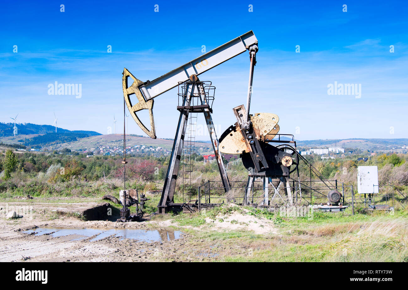 Öl- und Gas-Industrie. Arbeit von Öl Pumpe Jack auf einem Ölfeld. Weiße Wolken und blauer Himmel Stockfoto