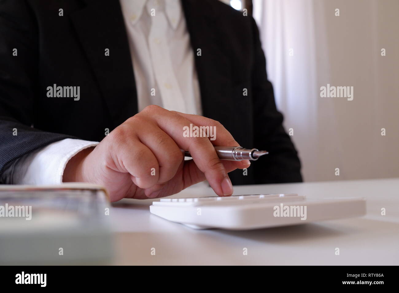 Geschäftsmann mit Taschenrechner mit Geld auf dem Schreibtisch Stockfoto