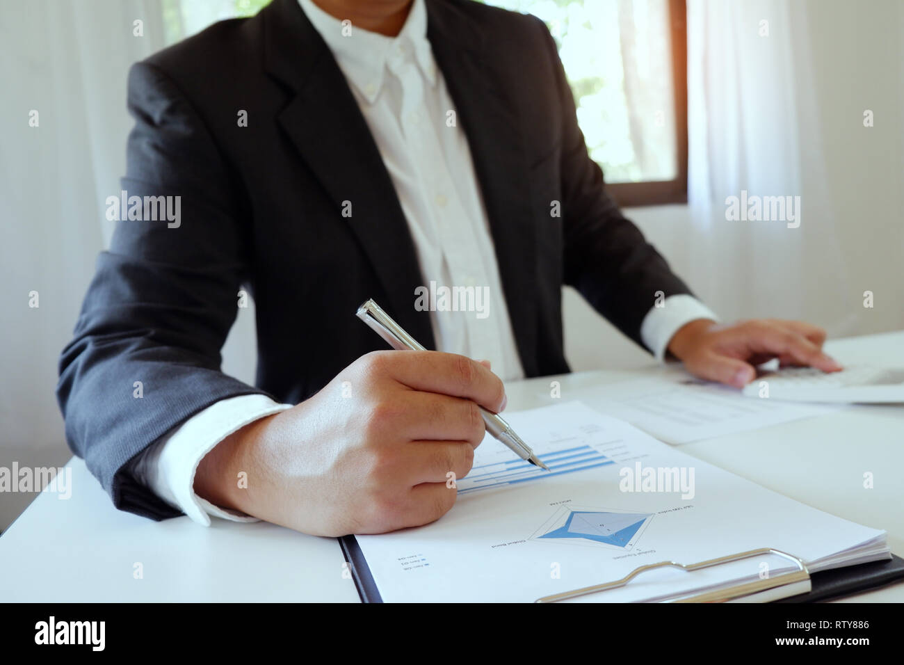 Unternehmer, die in Office mit Taschenrechner mit Dokument auf Schreibtisch Stockfoto