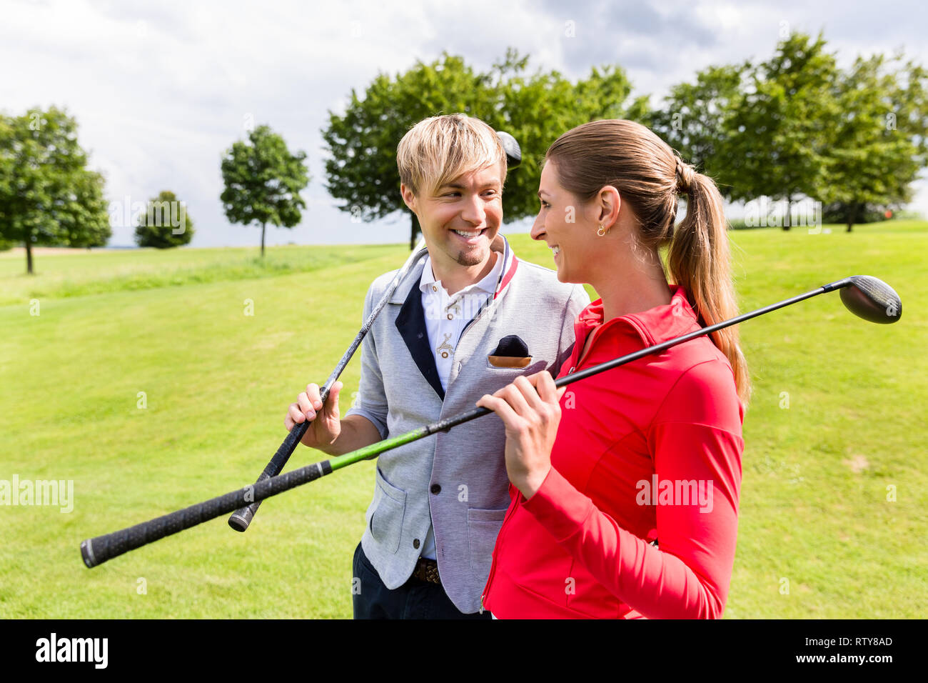 Paar hält Golf Club an jedem anderen Suchen Stockfoto