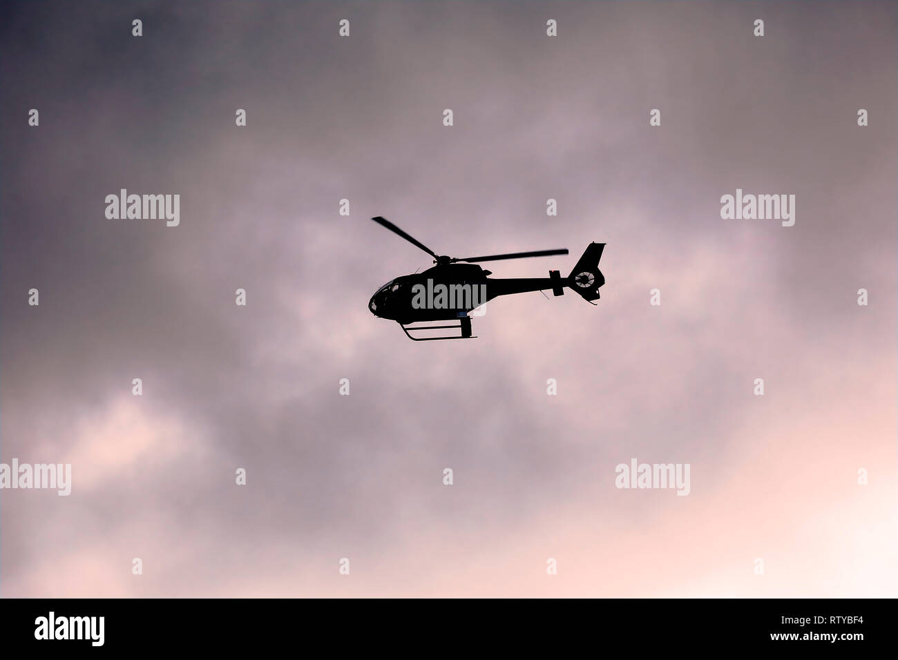 Hubschrauber fliegt in Silhouette gegen die drastischen bewölkter Sonnenuntergang Himmel. Kopieren Sie Platz. Stockfoto