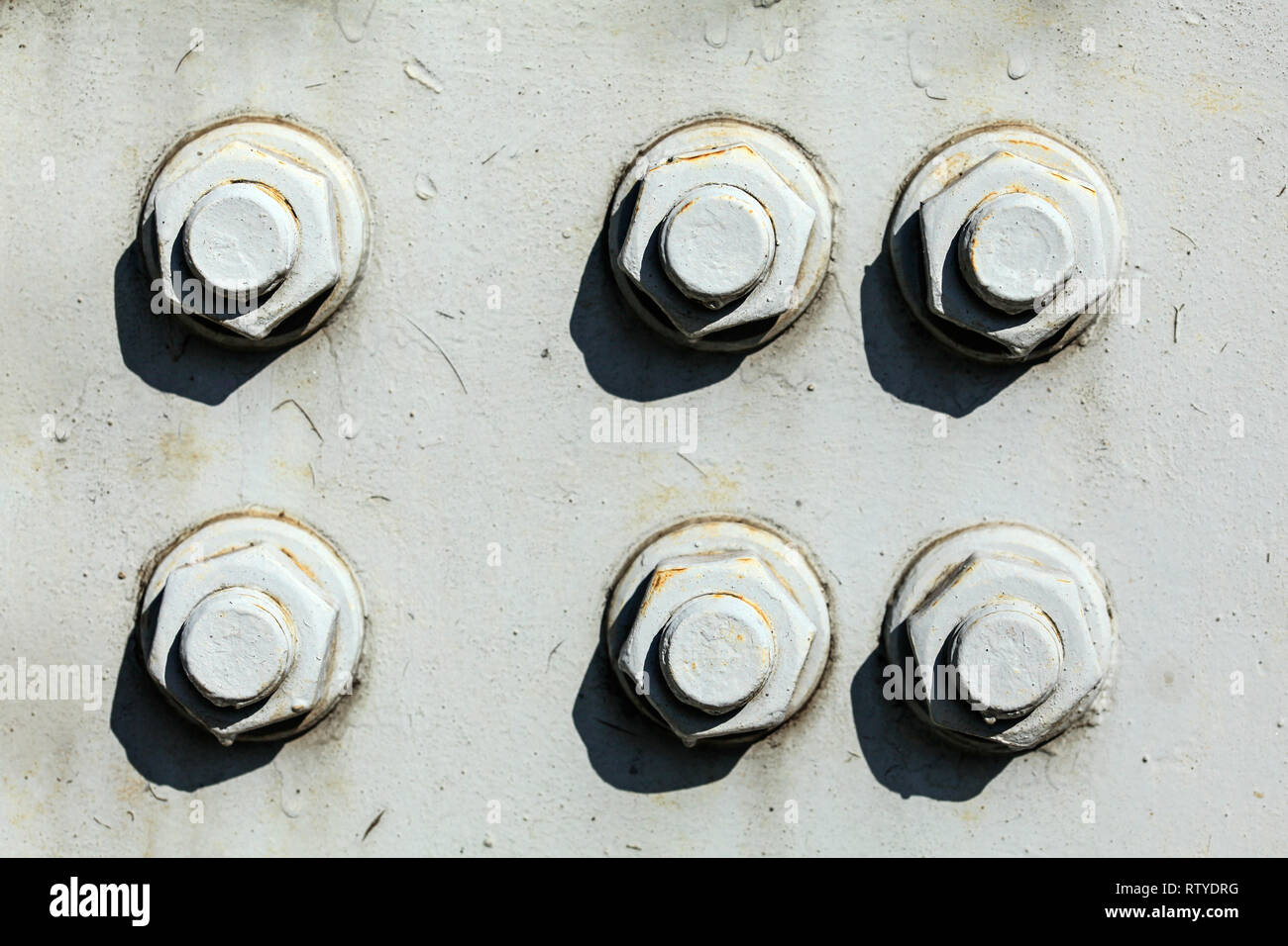 Sechs große Schrauben und Muttern auf grauem Stahlblech Rail Bridge, beleuchtet durch die helle Sonne. Abstrakte industriellen Hintergrund. Stockfoto