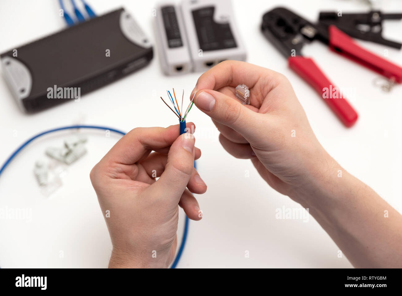 Techniker holding Twisted Pair Kabel Internet und RJ45-Stecker. Techniker Reparatur Netzwerk mit Kabel-Crimpzange Stockfoto