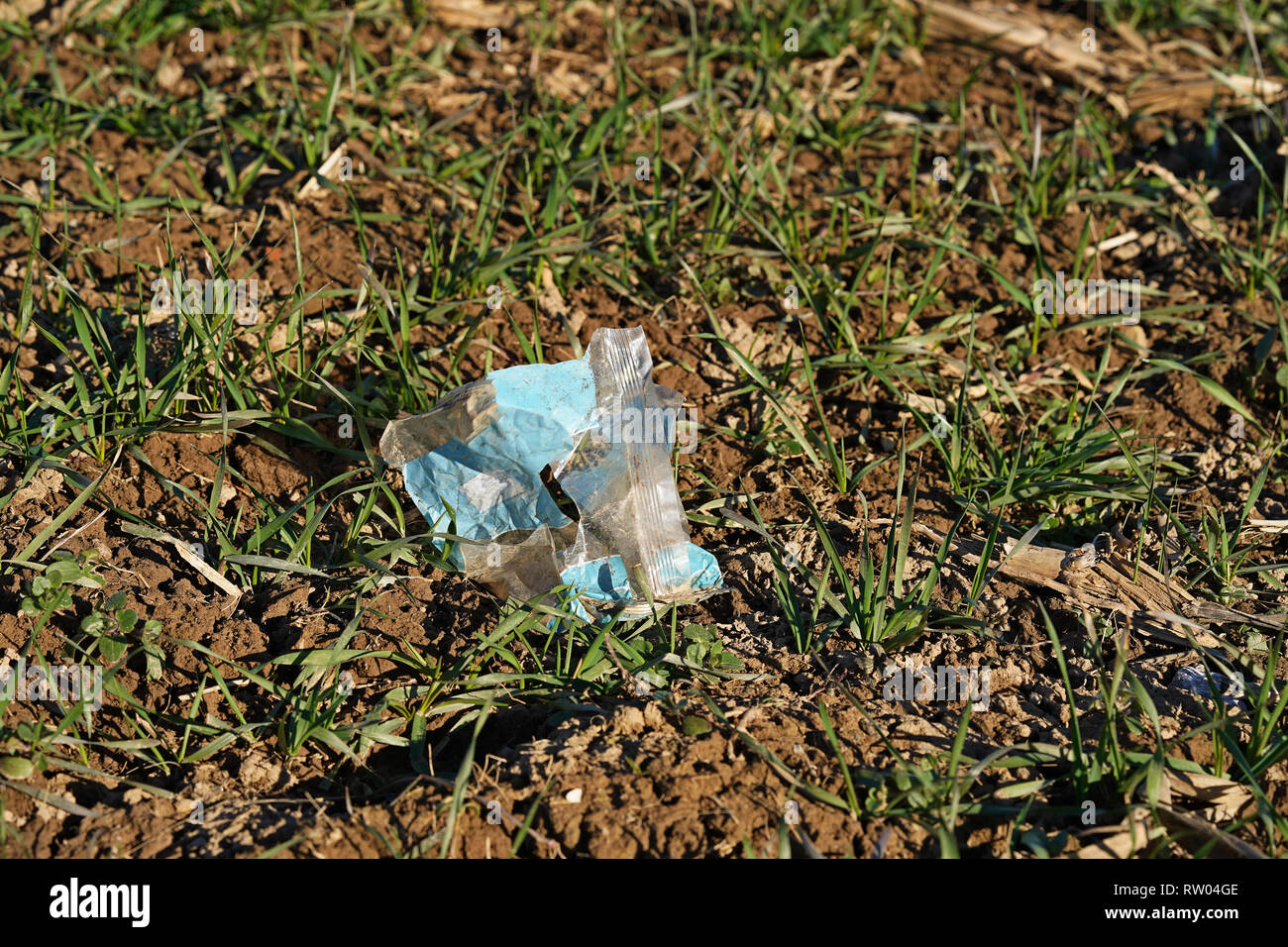 Kunststoff nicht verrottendem Abfall Verschmutzung durch weggeworfene Verpackung auf normales Feld zwischen Boden Krümel Stockfoto