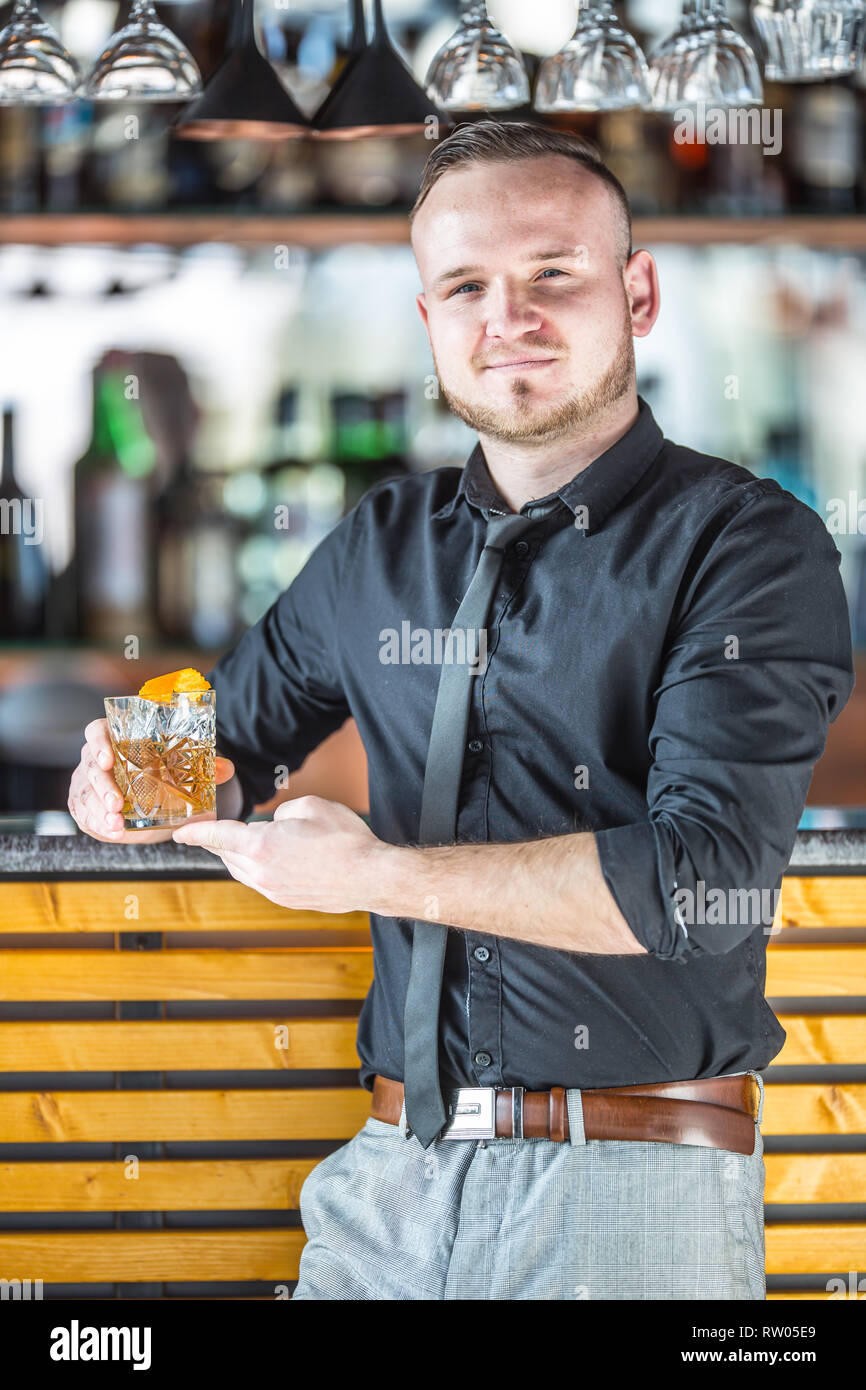 Barkeeper stand vor der Bar und in der Hand einen Cocktail trinken. Stockfoto