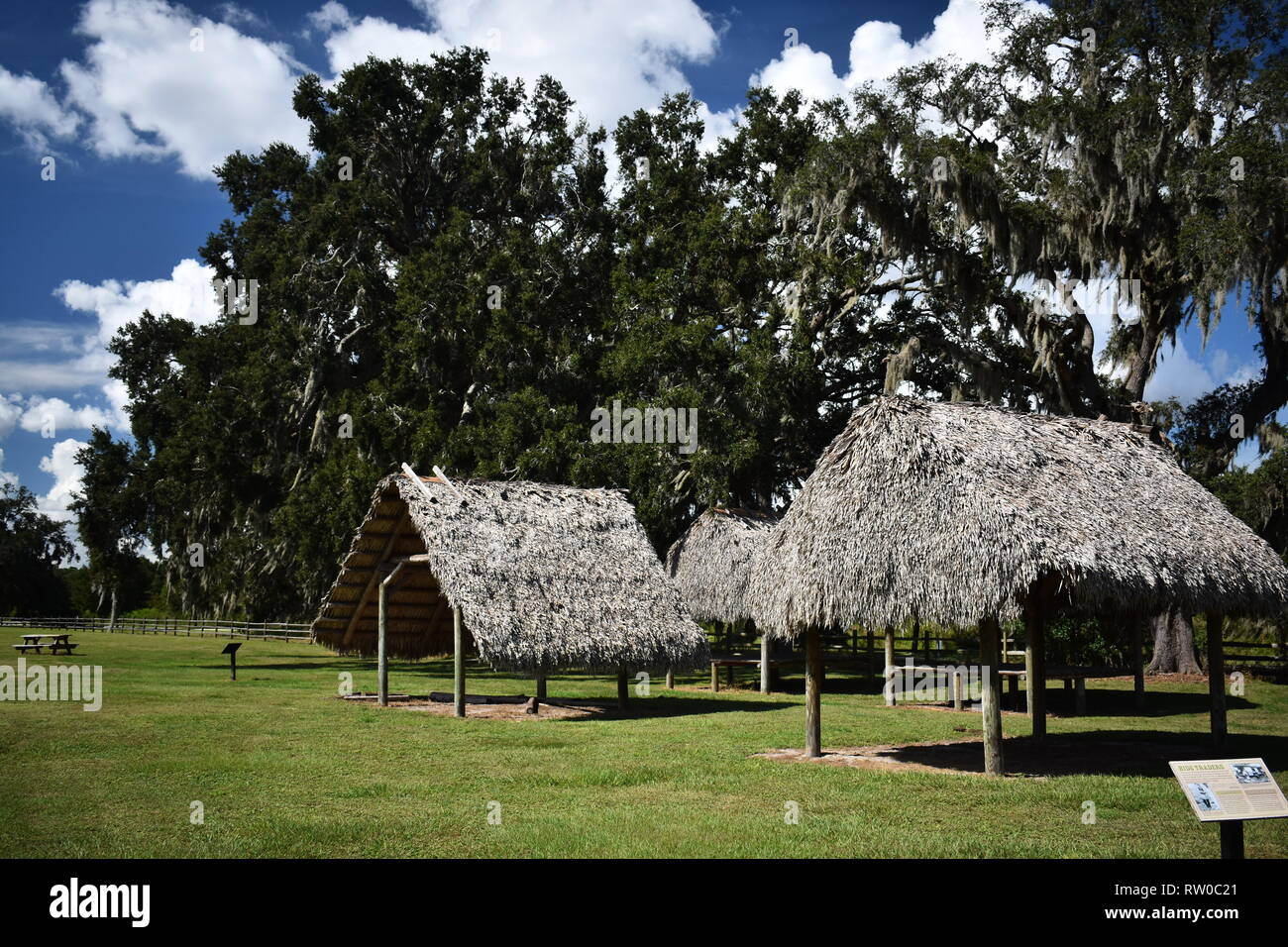 Traditionelle Seminole oder Miccosukee chickees Schatten bietet im Sommer mit grünen Bäumen im Hintergrund. Shingle Creek Pioneer Village, Kissimmee, FL, USA Stockfoto