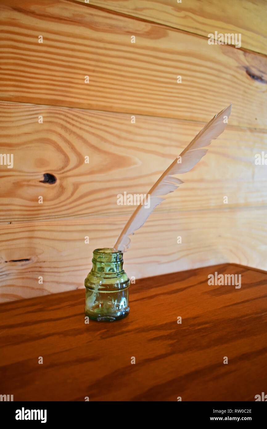 Antikes Glas Tintenfass mit Feder auf Holzregal mit einfachen Holz- Hintergrund. Shingle Creek Pioneer Village, Kissimmee, Florida, USA. Stockfoto