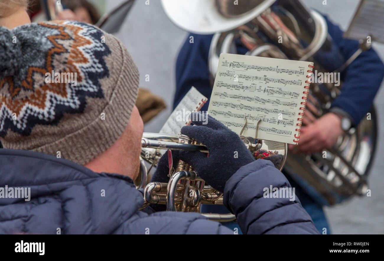 Eine Posaune in einer Brass Band zu Weihnachten. Der Mann in eine Wollmütze ist das Lesen von Musik während er Weihnachtslieder in einer Brass Band spielt. Stockfoto