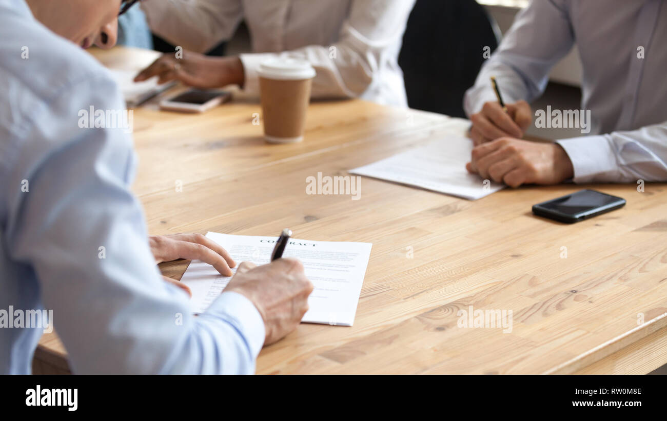 Geschäftsleute, die am Tisch sitzen während der Konferenz eine Vereinbarung unterzeichnen Vertrag Stockfoto