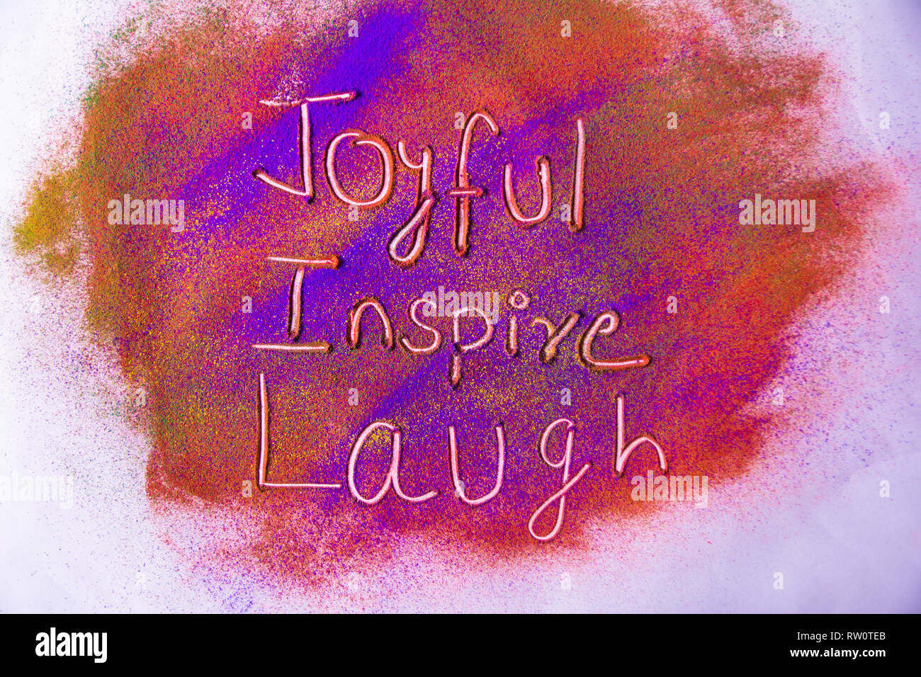 Freude, Lachen und Inspire Wort auf bunten Pulver Stockfoto