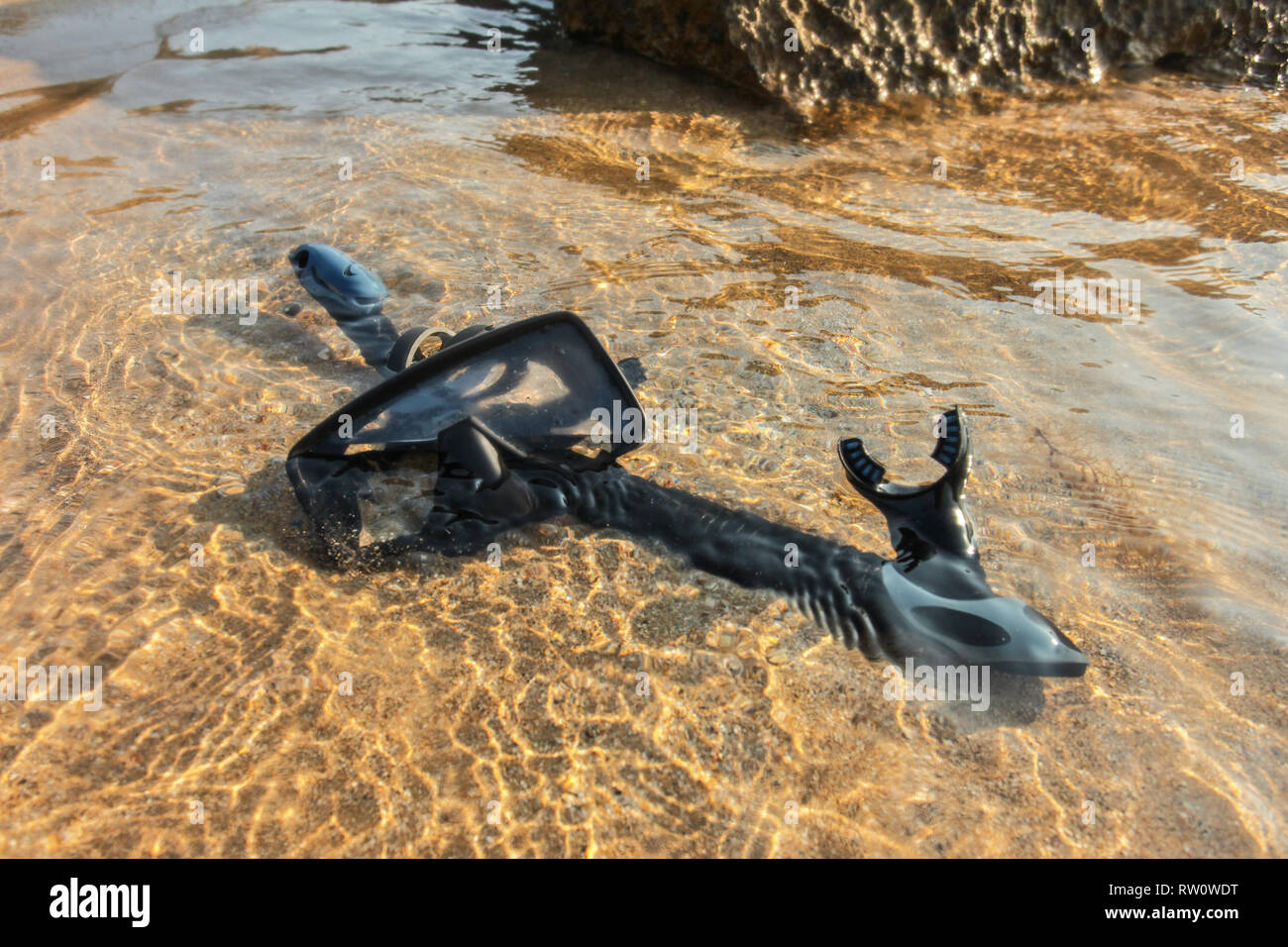 Schwarz Schnorcheln und Tauchen Maske/Brille auf Sand im flachen Meer Wasser. Stockfoto