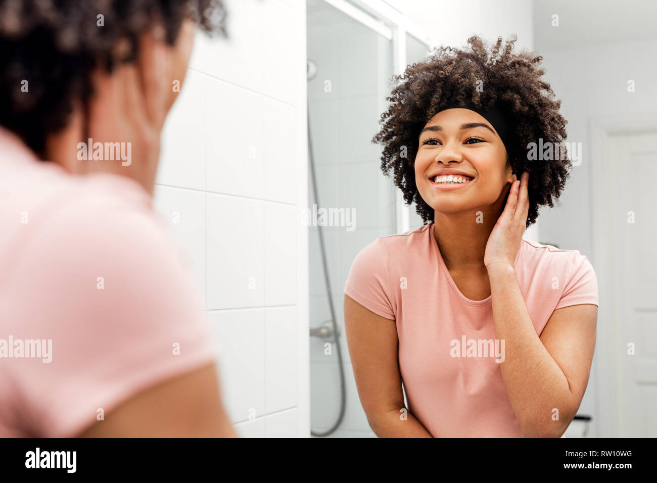 Glückliche junge Frau stand vor der Spiegel im Bad Stockfoto