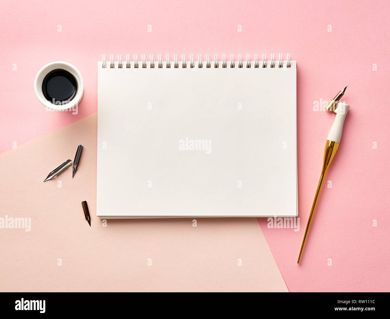 Mock up von leeren artist Skizzenbuch auf rosa Hintergrund mit Kalligraphie Feder und Tinte. Die Aussicht von oben. Stockfoto