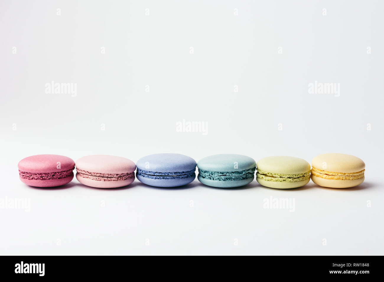 Reihe der bunte Macarons auf weißem Hintergrund. Ansicht von oben. Stockfoto