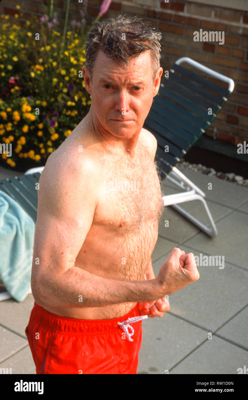 Im mittleren Alter Mann Verbiegen im Spaß bei einem Schwimmbad, USA Stockfoto