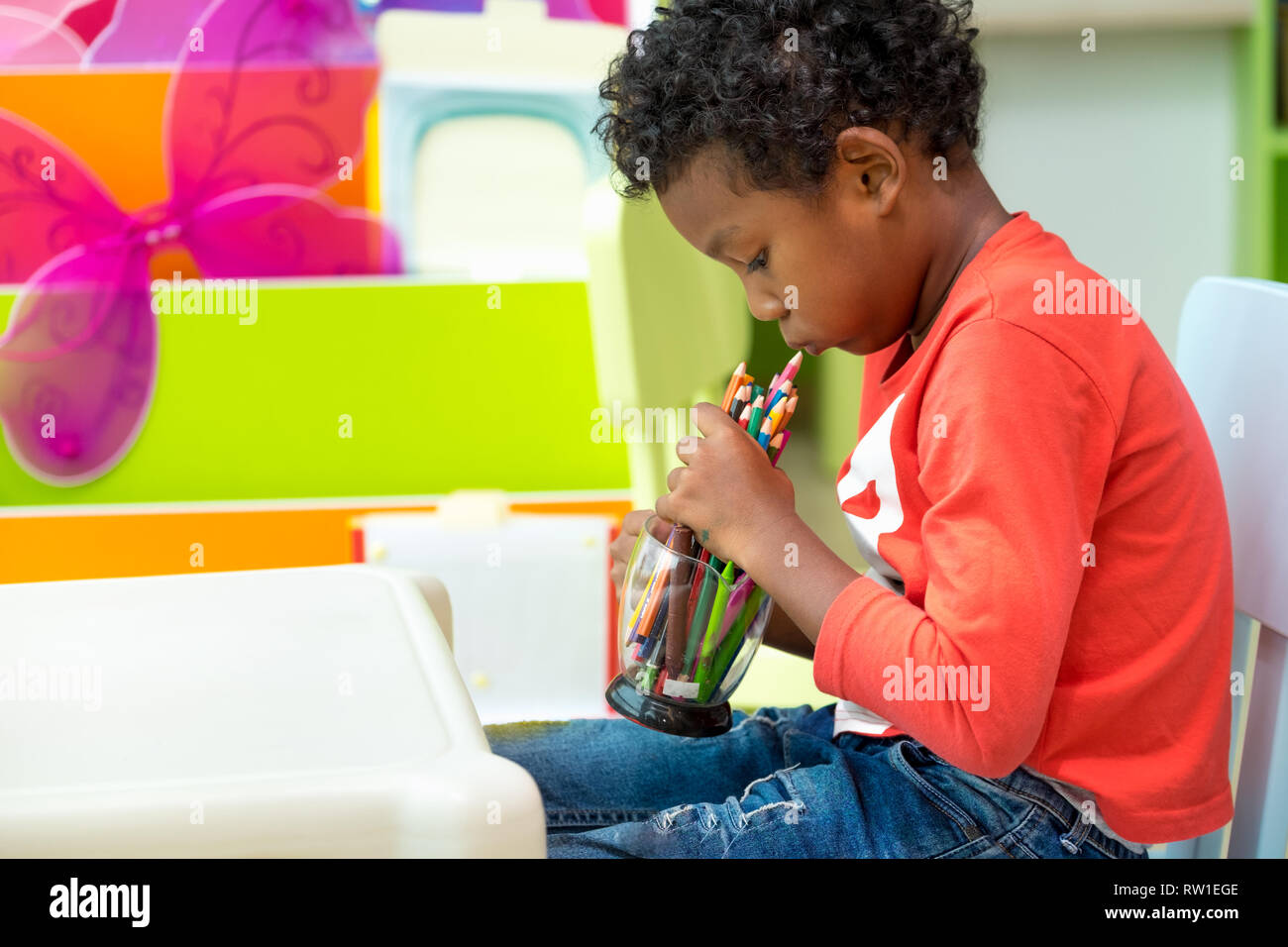 Schwarz-amerikanischen Jungen spielen mit Farben Bleistift allein im Klassenzimmer im Kindergarten Vorschule, Bildung Konzept Stockfoto