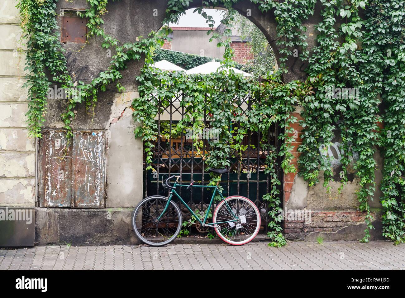 Bike vor einem Tor mit grünen Blättern bewachsen geparkt, Kazimierz in Krakau, Polen Stockfoto