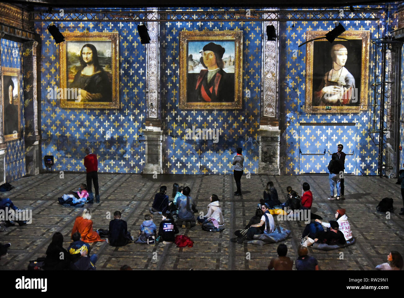 03. März 2019, Sachsen, Leipzig: Während die Multimedia Show "LEONARDO DA VINCI, Raffael, Michelangelo, Riesen der Renaissance' in der Kunstkraftwerk, die Besucher werden Die da Vinci Gemälde "Mona Lisa", "Porträt eines jungen Mannes" und "Dame mit dem Hermelin" (L-R), die auf den Mauern der ehemaligen Maschinenhalle, die bis zu acht Meter hohen projiziert werden. Die außergewöhnliche Multimedia Projektion der italienischen Immersive Kunst Fabrik, die anlässlich des 500. Geburtstags von Leonardo da Vincis Tod gezeigt werden wird, wurde bereits von über 8000 Besucher seit der Eröffnung auf gesehen worden Stockfoto