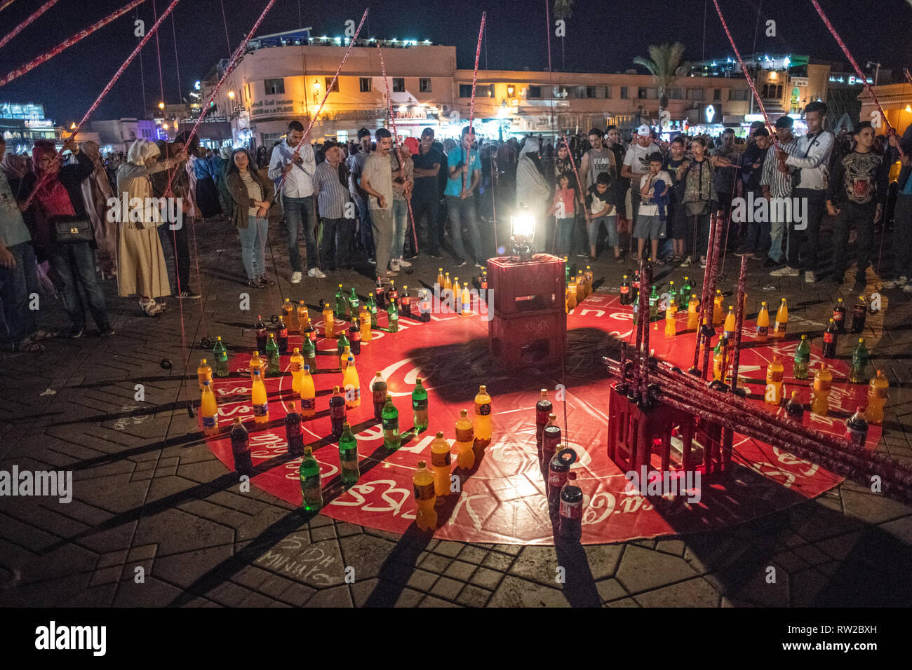 Gruppe von Menschen fischen spielen - pole Spiel mit Limonade Flasche in Jemaa el-Fnaa Platz bei Nacht, Marrakesch, Marokko Stockfoto