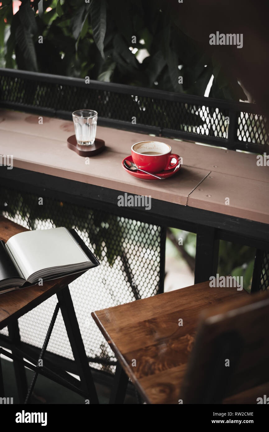 Abstrakte emotionale Szene von heißem Kaffee in rot Tasse Kaffee am Tisch im Cafe am Morgen Zeit. Wochenende Aktivität und Entspannung. lieblingsgetränk Konzept o Stockfoto