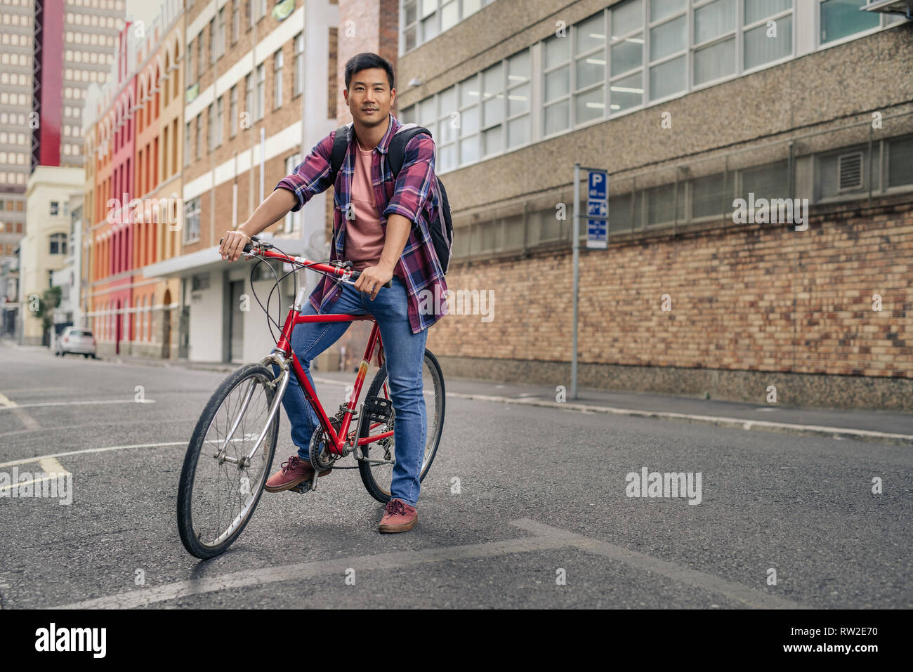 Lächelnden jungen Mann sitzt auf seinem Fahrrad in der Stadt Stockfoto
