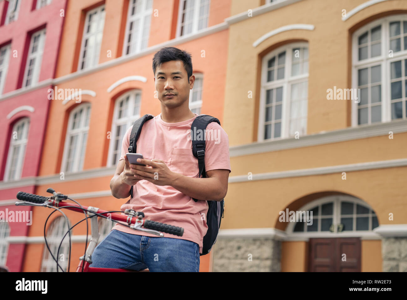 Jungen asiatischen Mann sitzt auf seinem Fahrrad mit einem Mobiltelefon Stockfoto