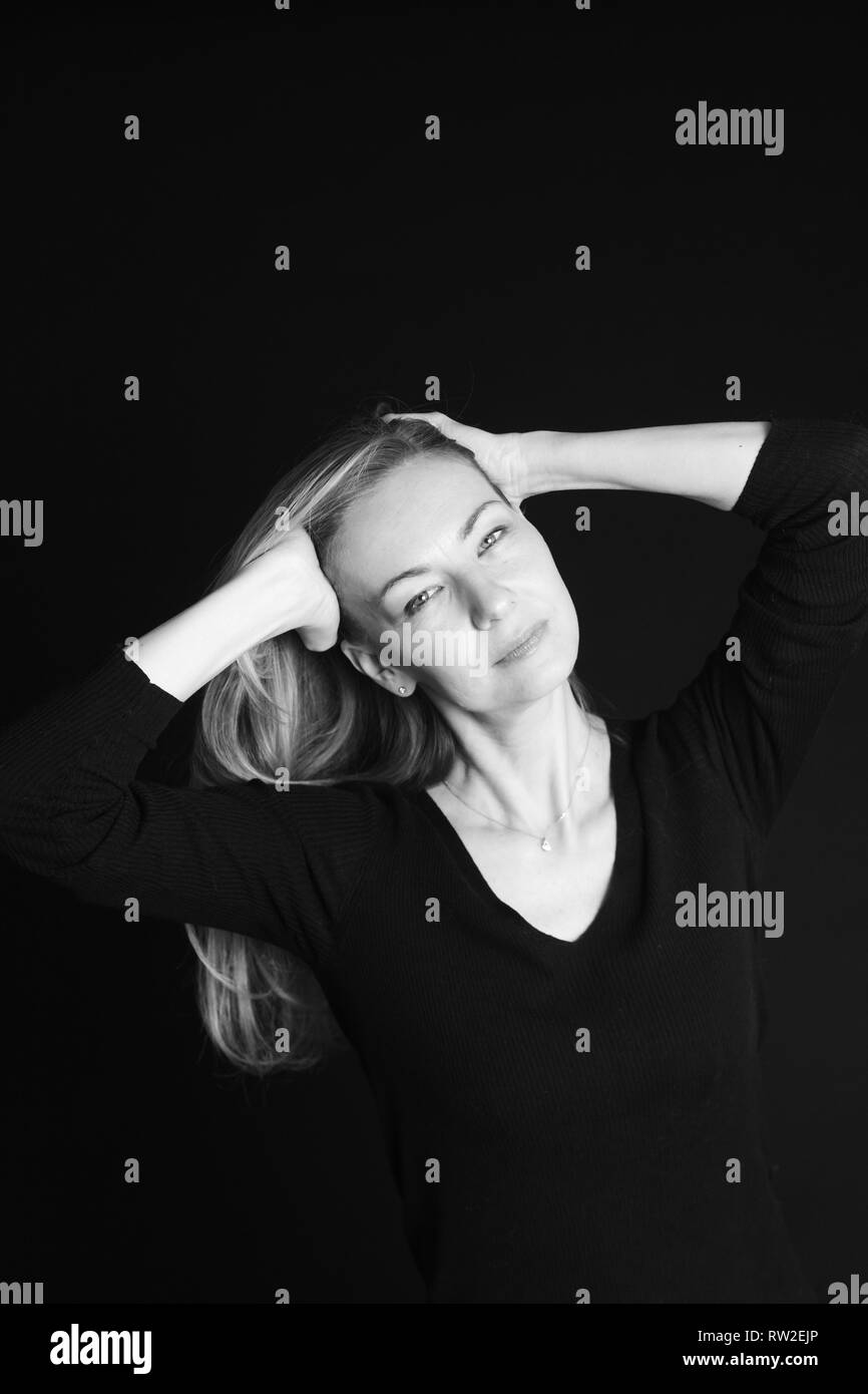In der Nähe von Studio Portrait einer schönen Frau im schwarzen Kleid auf schwarzem Hintergrund Stockfoto
