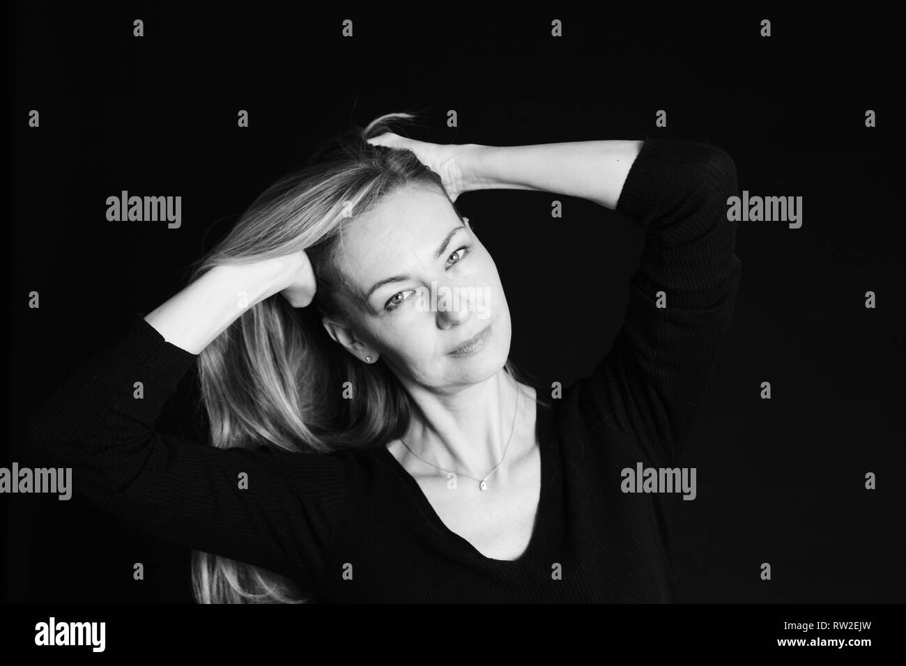 In der Nähe von Studio Portrait einer schönen Frau im schwarzen Kleid auf schwarzem Hintergrund Stockfoto