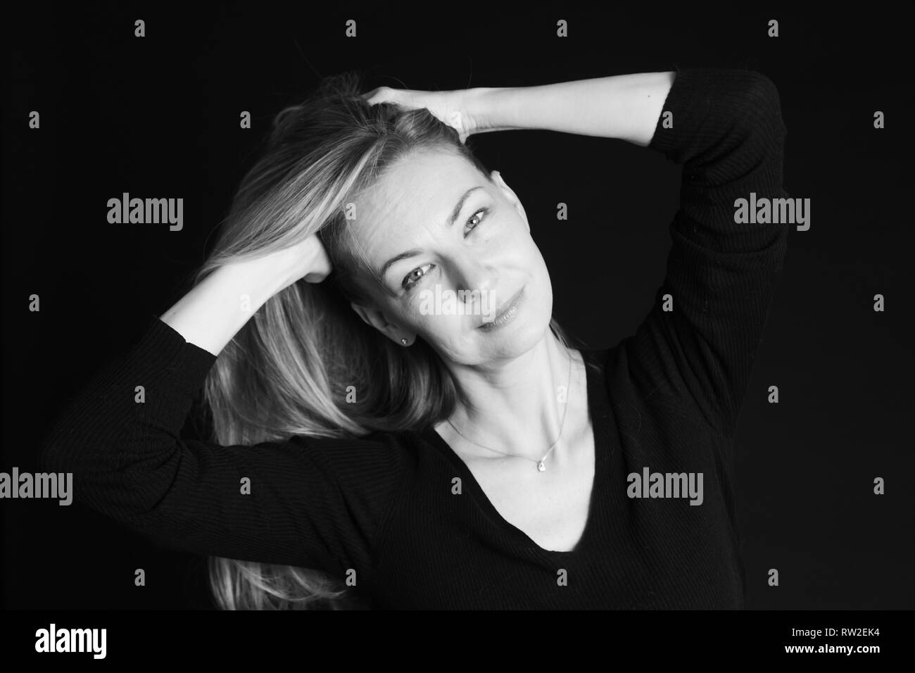 In der Nähe von Studio Portrait einer schönen Frau im schwarzen Kleid auf schwarzem Hintergrund Stockfoto