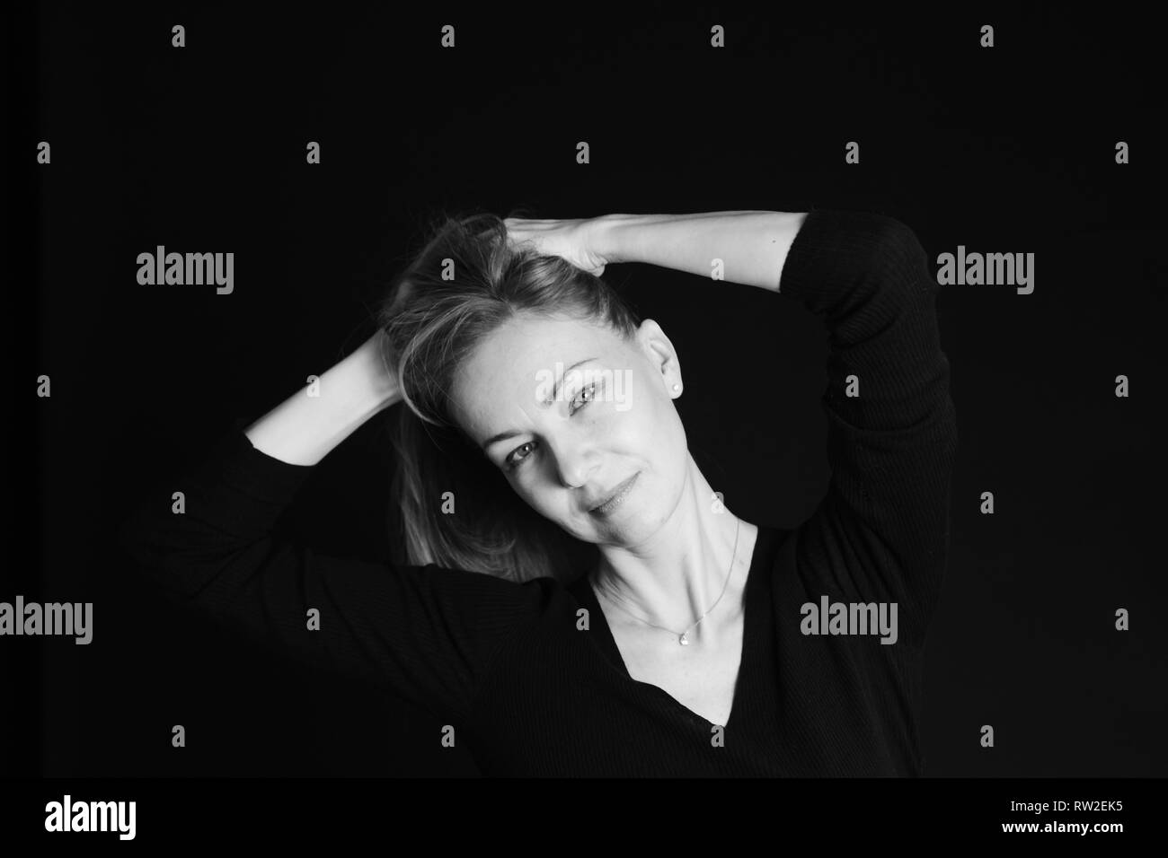 In der Nähe von Studio Portrait einer schönen Frau im schwarzen Kleid auf schwarzem Hintergrund Stockfoto