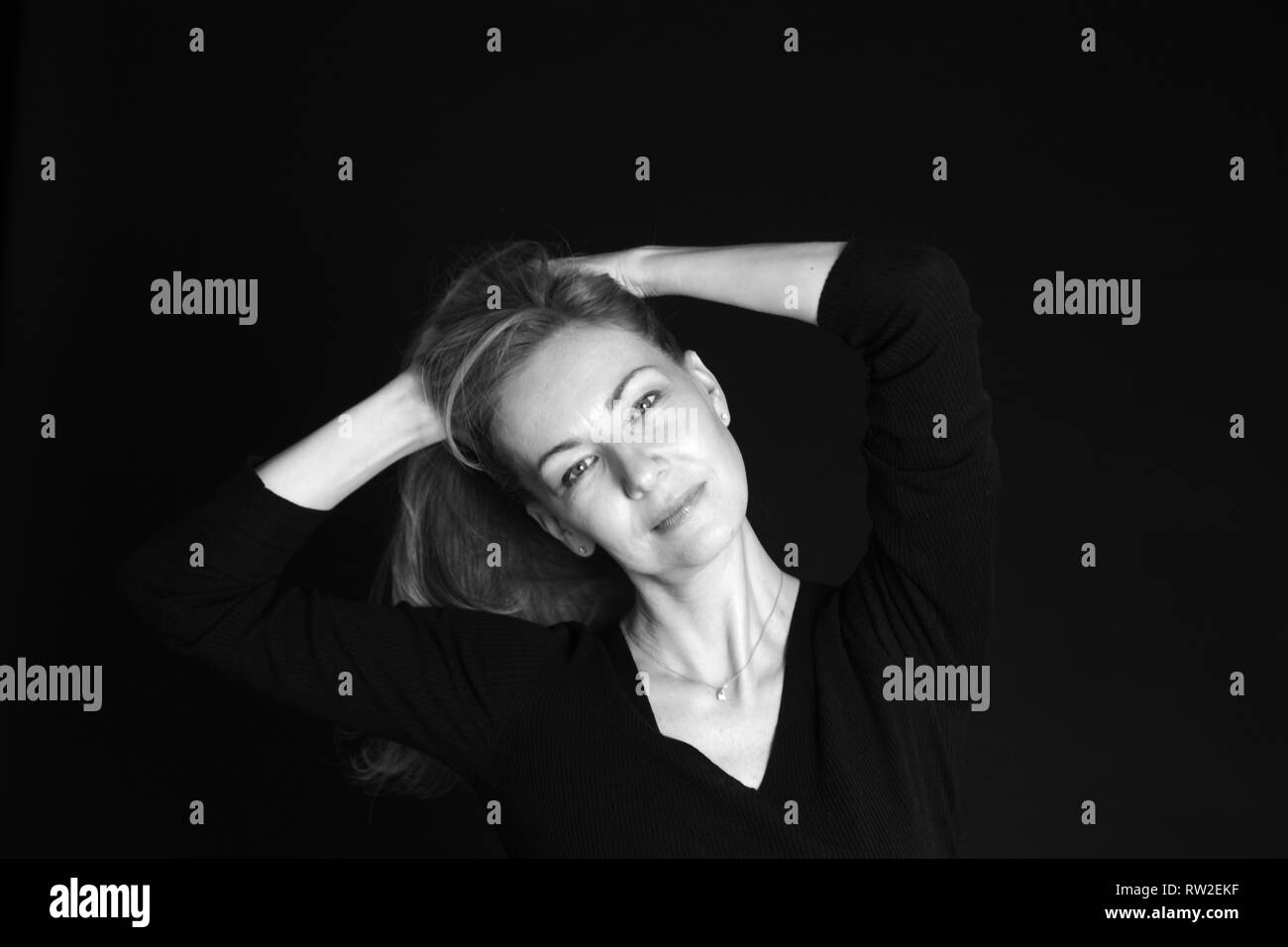 In der Nähe von Studio Portrait einer schönen Frau im schwarzen Kleid auf schwarzem Hintergrund Stockfoto
