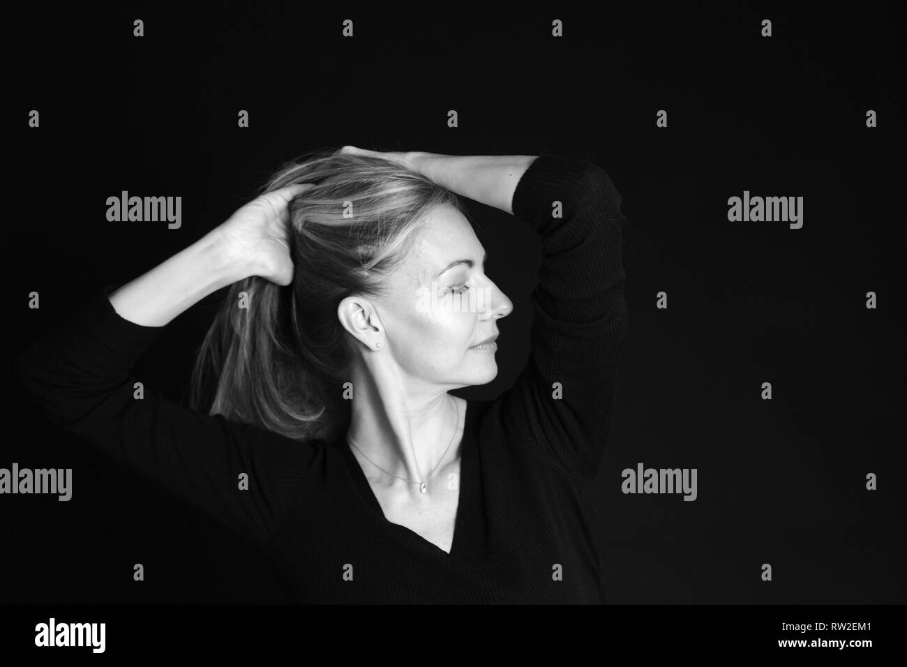 In der Nähe von Studio Portrait einer schönen Frau im schwarzen Kleid auf schwarzem Hintergrund Stockfoto