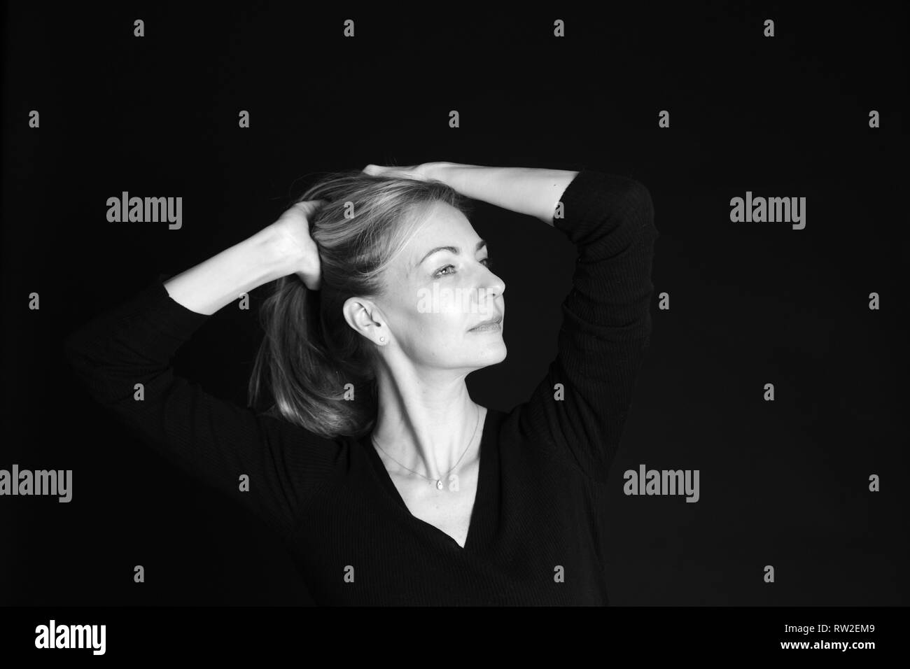 In der Nähe von Studio Portrait einer schönen Frau im schwarzen Kleid auf schwarzem Hintergrund Stockfoto