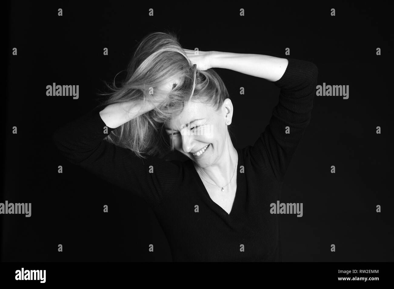 Nahaufnahme, Porträt einer Frau mit einem dummen Moment, während gegen den schwarzen Hintergrund posiert im Studio Stockfoto