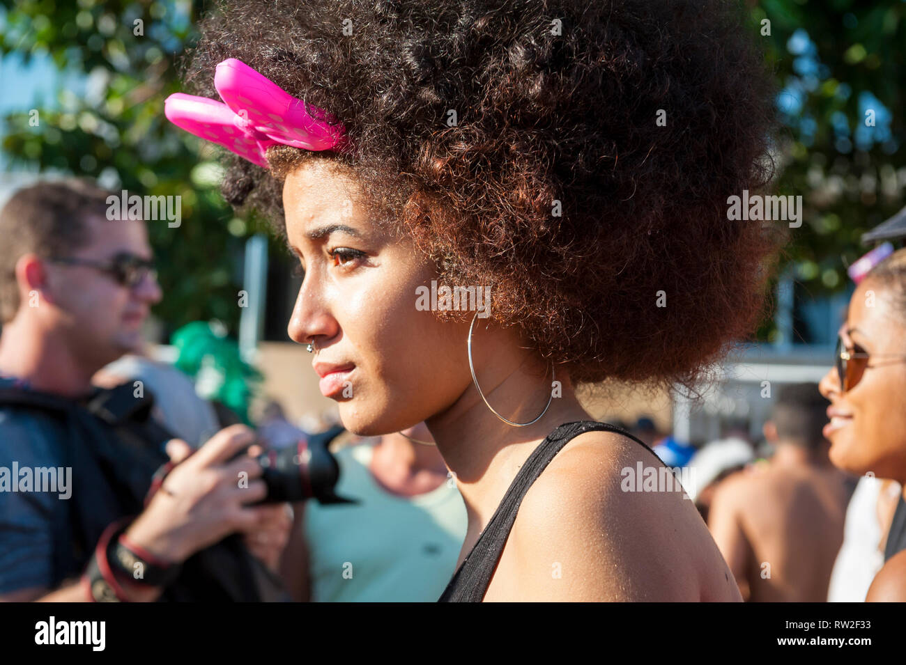 RIO DE JANEIRO - 18. FEBRUAR 2017: Eine junge brasilianische Frau trägt eine rosa Schleife in Ihrem afro als dezente Karneval Kostüm an einem Straßenfest. Stockfoto