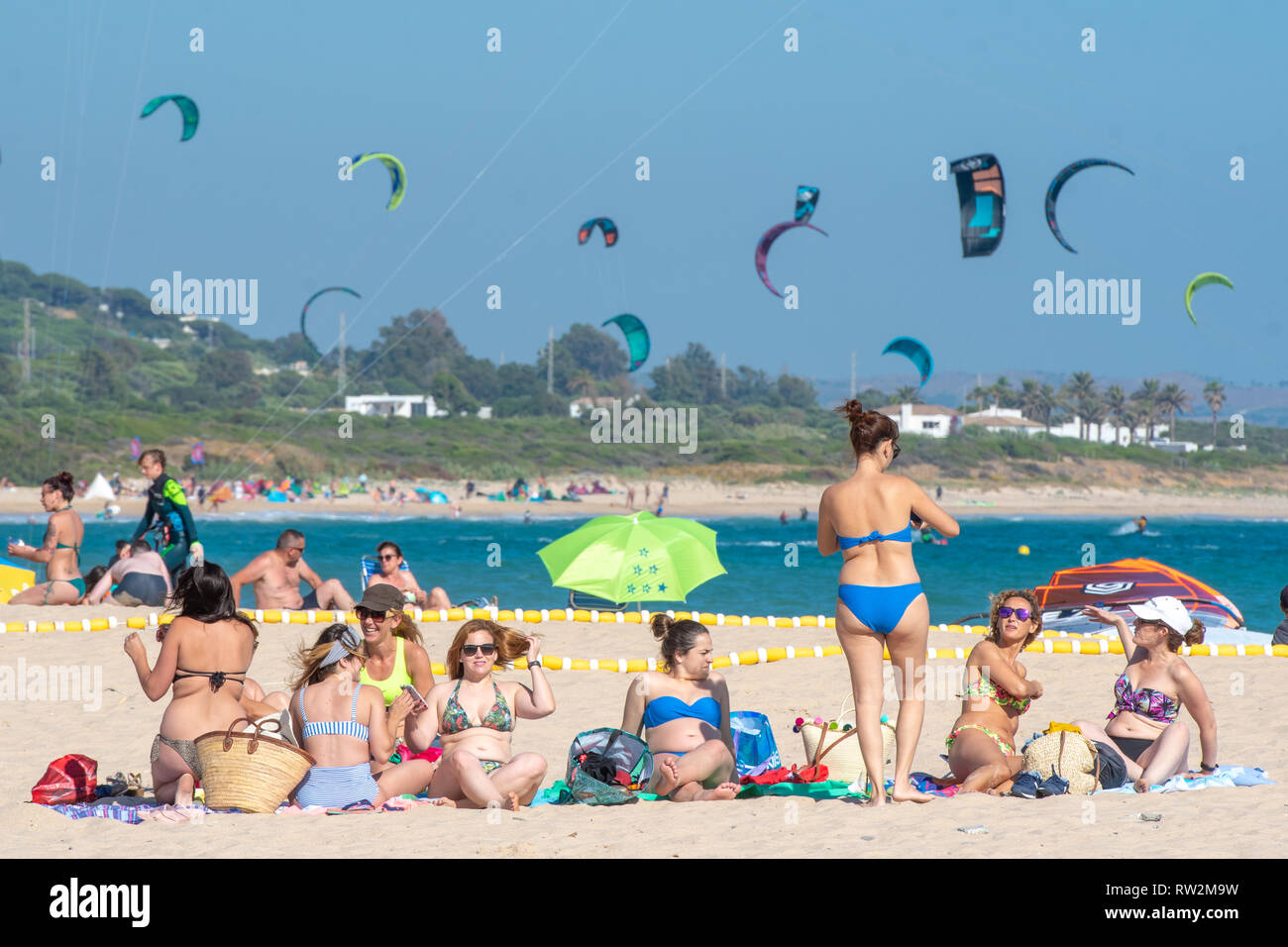 Frau am Strand mit Drachen fliegen im Hintergrund, Tarifa, Cádiz, Andalusien, Spanien Stockfoto