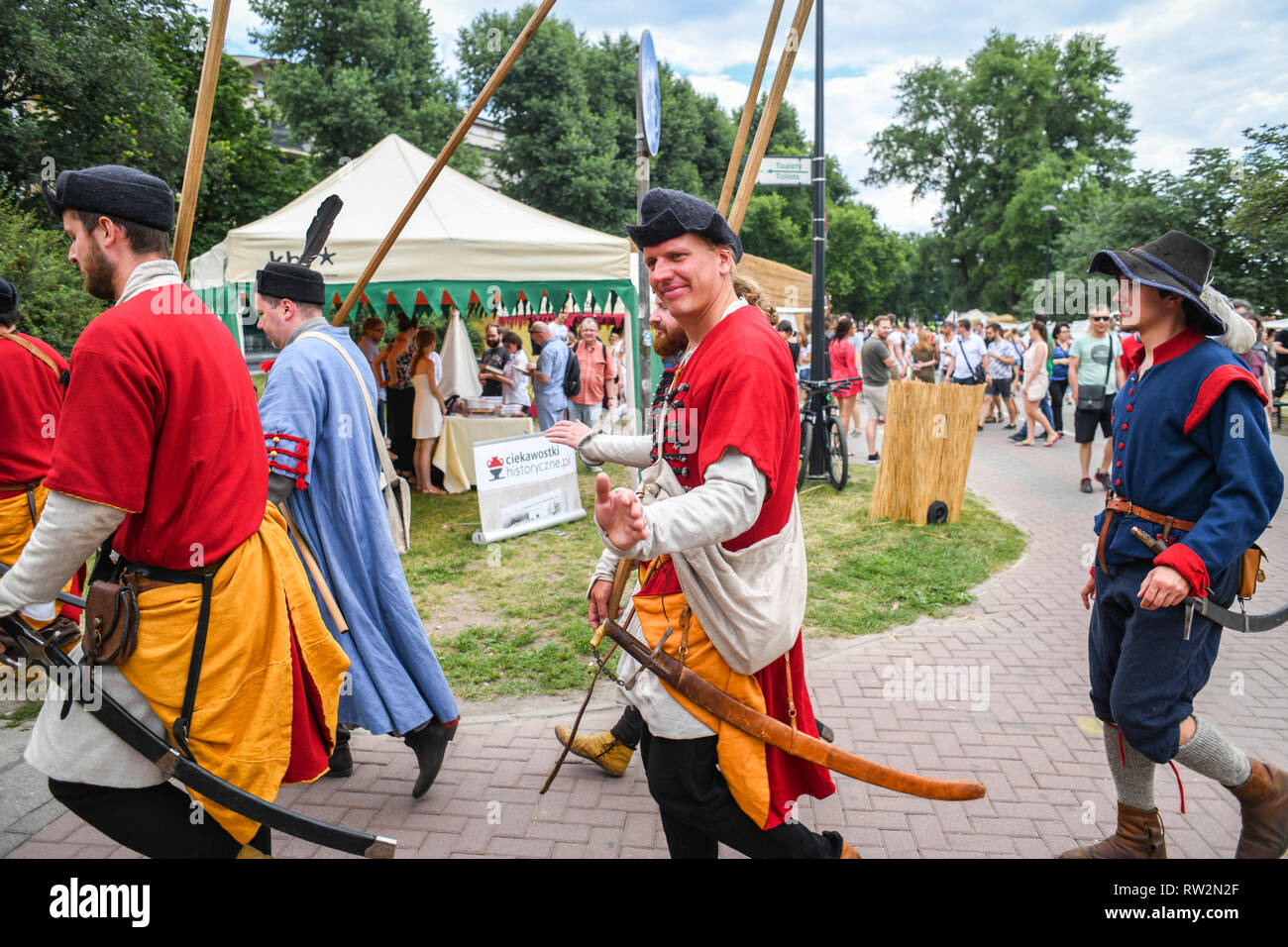 Männer, gekleidet in der mittelalterlichen Periode Kostüme und Lanzen wave zu den Zuschauern bei der jährlichen St John's Fair - Jahrmarkt - Świętojański, Kraków, weniger Stockfoto