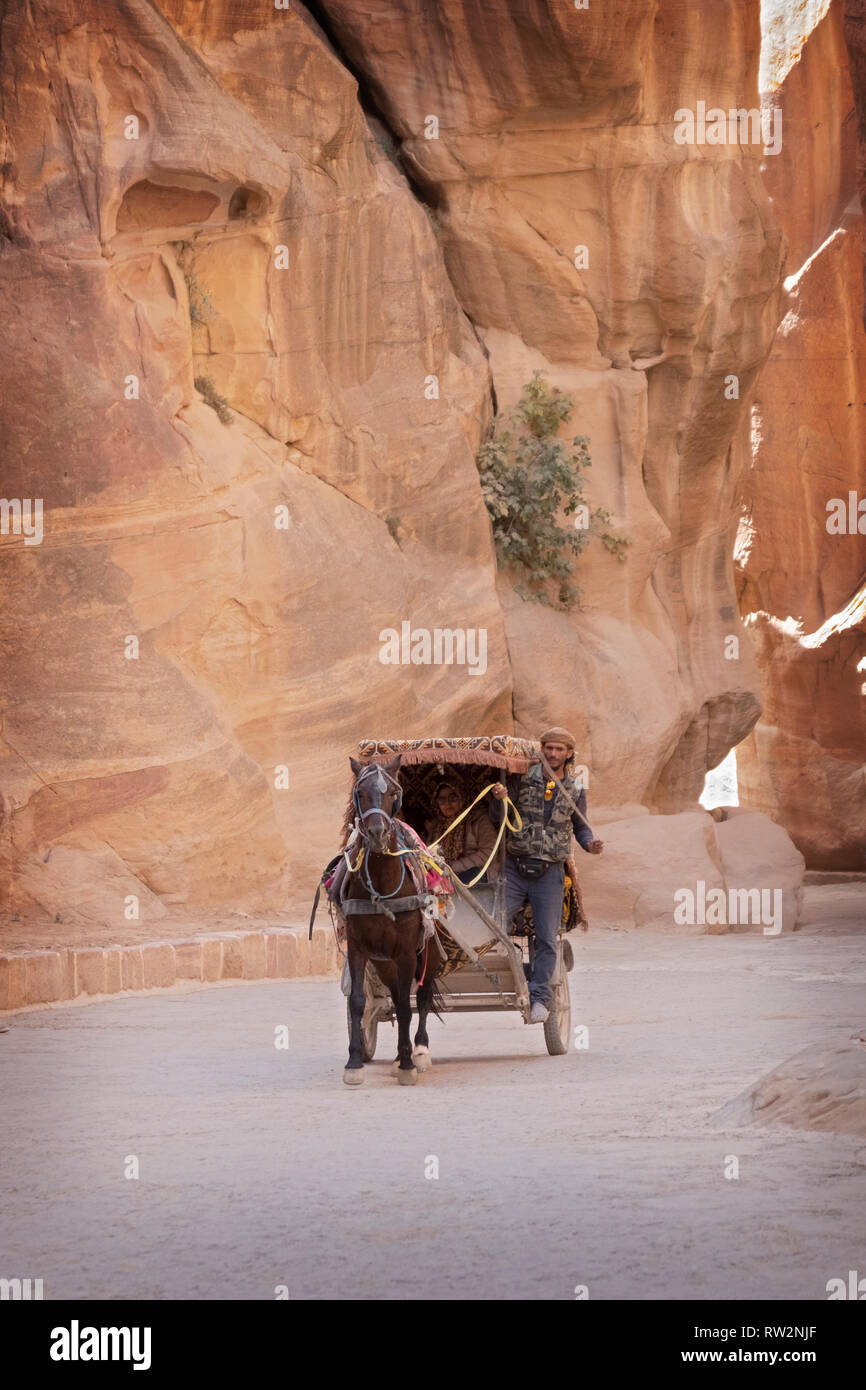 PETRA. Ein jordanischer Pferd und Kutsche Taxi Driver und seine weiblichen Passagier Fahrt durch die Felsen aus dem Treasury Gebäude auf den Bereich verlassen. Stockfoto