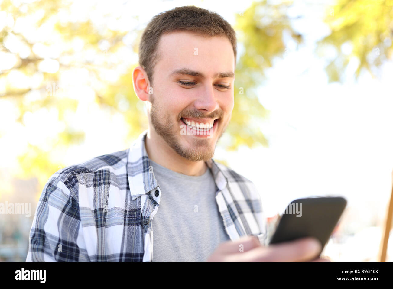 Portrait eines glücklichen Menschen mit einem smart phone Wandern in einem Park Stockfoto