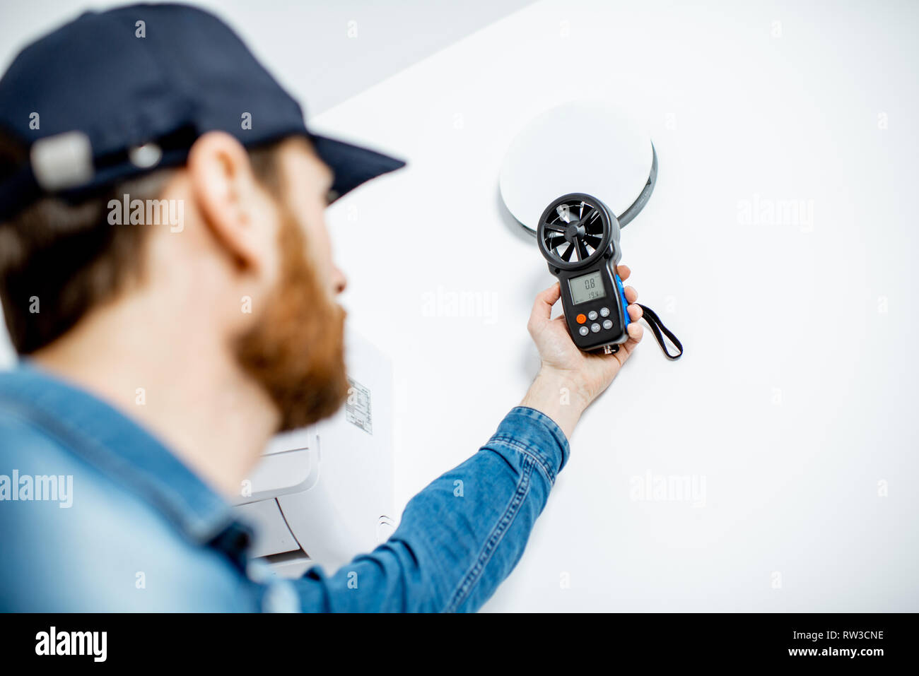 Heimwerker Kontrolle der Geschwindigkeit der Belüftung mit Messgerät auf der weißen Wand Hintergrund Stockfoto