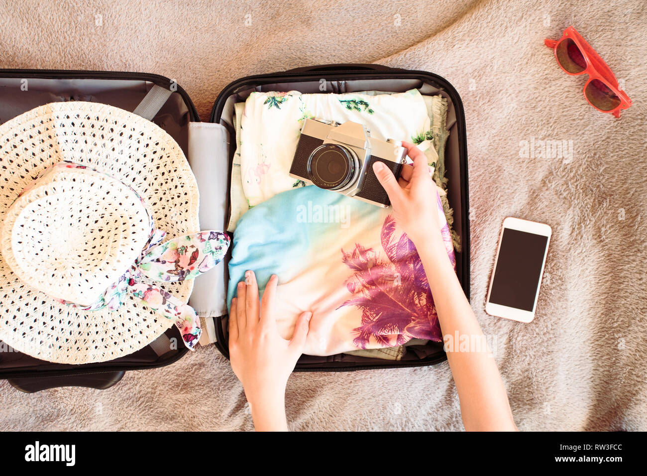 Zeit für die Sommerferien. Koffer mit gepackten Sommer Kleidung, eine Kamera, einen Hut und Sonnenbrille Stockfoto