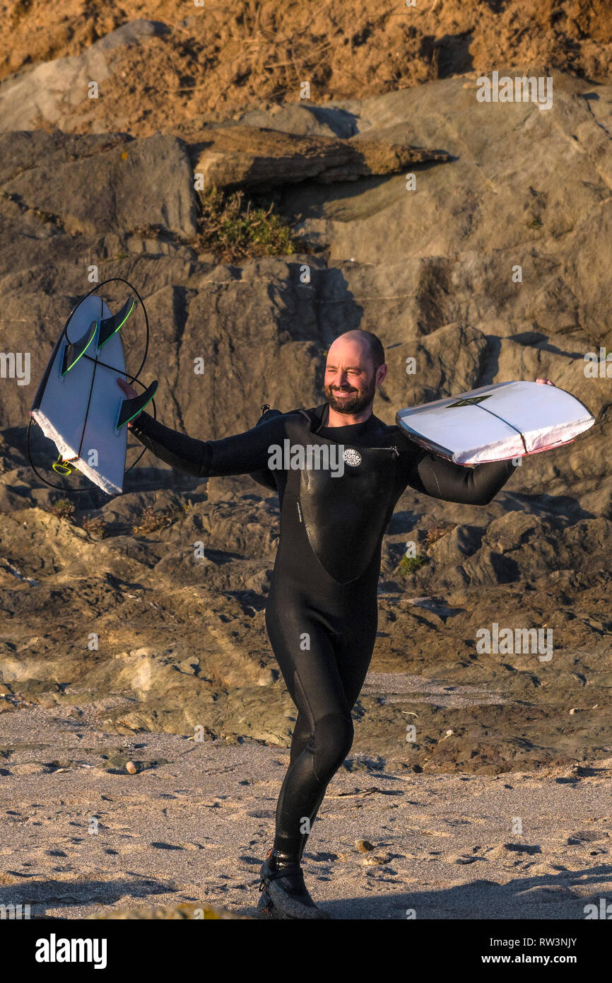 Ein lächelndes Surfer auf Felsen bis Holding und Anzeige der Riß Surfbrett an der North Fistral in Newquay Cornwall. Stockfoto