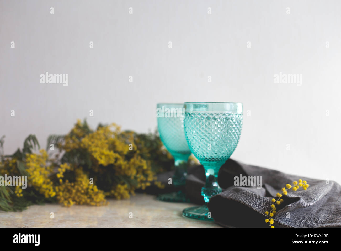 Blue Vintage Kelche und gelben Mimosen, Blumen. Weingläser auf whight Hintergrund. Stockfoto