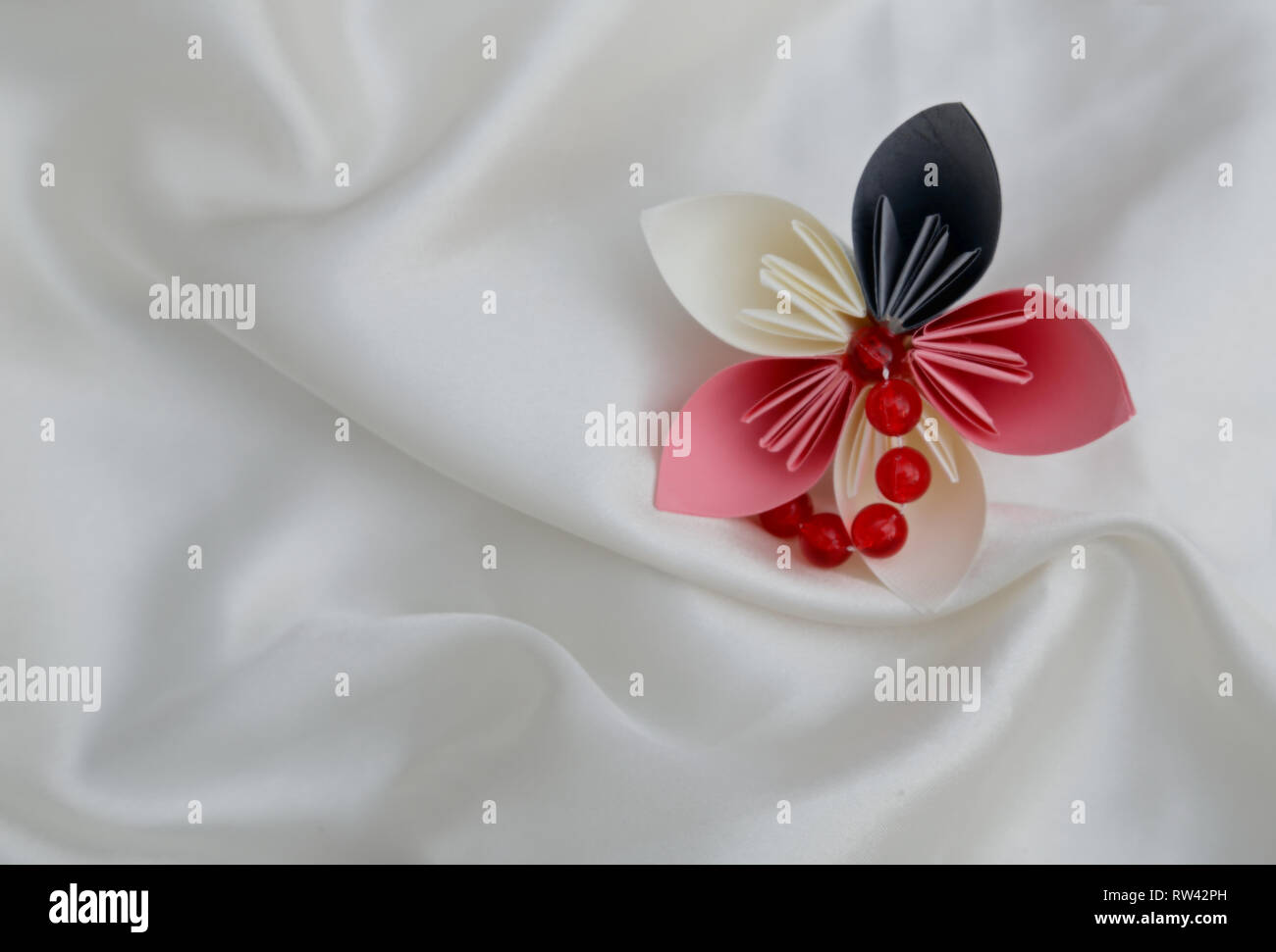 Schöne bunte gefaltet origami Blume auf einem weißen glänzenden Background Stockfoto