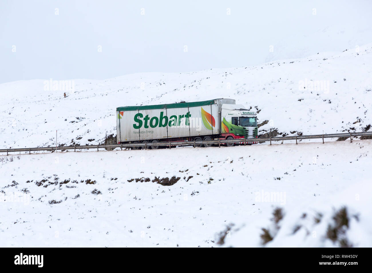 Stobart Truck, den das Fahrzeug entlang der A82 Straße am Tag der Winter mit Schnee um an Rannoch Moor, Glencoe, Highlands, Schottland im Winter Stockfoto