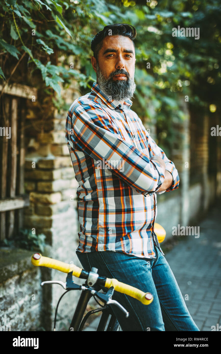 Ein hübscher junger Mann geht in die Stadt mit dem Fahrrad, daneben stehen und warten, dass jemand. Stockfoto